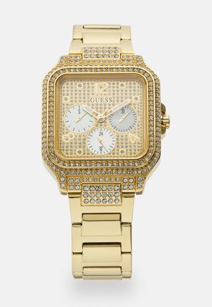 Gold watch with a square face, studded with crystals. Three sub-dials and a patterned gold background. Metal link bracelet design.