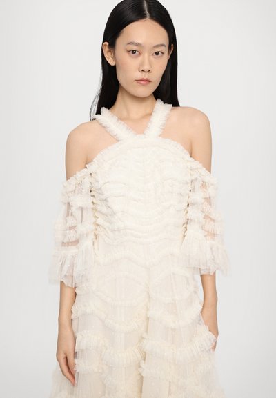 Witte jurk met textured ruffles en doorschijnende mouwen, met een halterhals en gelaagd ontwerpelement. Zachte stof met een subtiele glans.