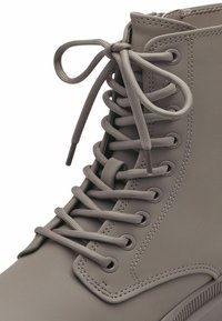 Szare gumowe kalosze z okrągłymi sznurówkami i wzmocnionymi oczkami, z widocznymi detalami przes stitchingowymi wzdłuż boków i górnych krawędzi.