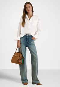 Valge pika varrukaga särk esitaskuga, helesinised laiad teksapüksid, pruun tassliga käekott ja pruuni punutud materjaliga madalad jalanõud.