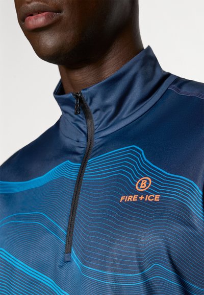 Sötétkék sport félcipzáras felső, kék hullámos mintával és „FIRE + ICE” narancssárga logóval. Álló gallérral és fekete cipzárral rendelkezik.