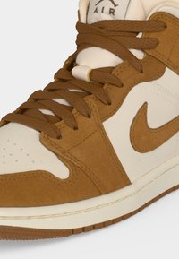 Κοντινό πλάνο ενός καφέ και άσπρου Nike Air sneaker με καφέ κορδόνια, επενδύσεις από σουέτ και το λογότυπο Nike swoosh στο πλάι.