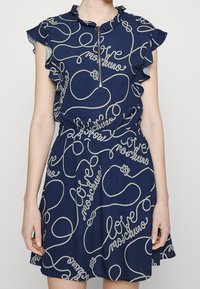 Marinblå klänning med volangärmar och dragkedja framtill. Har vit rep-stil "love" tryck, insnörd midja och utställd kjol.