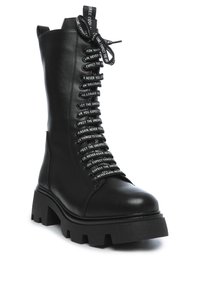 Botas de combate de cuero negro con suela gruesa y cordones negros impresos con texto blanco que dice "Espera lo inesperado" y "Nunca más".