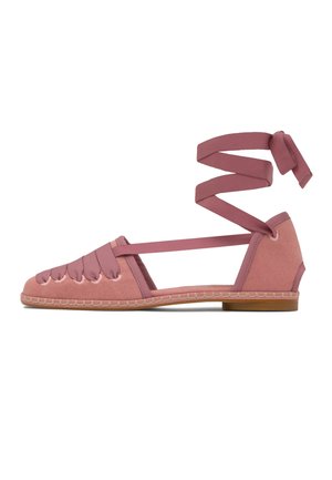 Różowa płaska espadrylka z zamkniętym noskiem, z krzyżującymi się detalami z tkaniny i wiązaniem wokół kostki na białym tle.