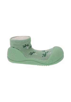 Zapato verde para bebé con suela blanda y calcetín integrado, con pequeños dibujos de palmeras y puntera y tacón de goma texturizada.