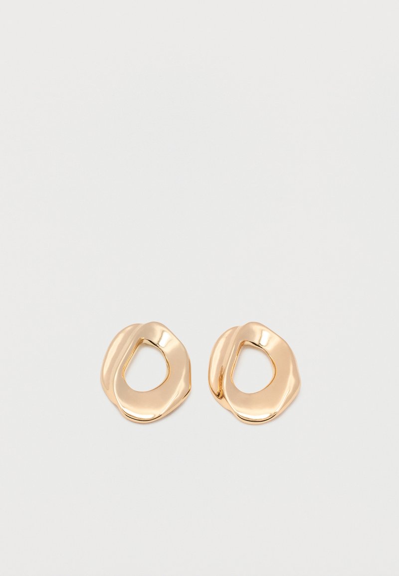 Ζευγάρι σκουλαρικιών κρίκος από μέταλλο σε χρυσή απόχρωση με γυαλιστερό φινίρισμα και ακανόνιστο σχήμα, με ανοιχτό κέντρο, σε λευκό απλό φόντο.