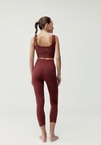 Bordový dvojdielny športový set s rebrovanou textúrou. Crop top má široké ramienka; legíny sú po členky s priliehavým strihom.