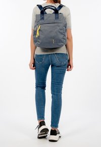 Grå och marinblå ryggsäck med en strukturerad design, som har en framficka, dubbla handtag och en gul dragkedja. Texturerat material.