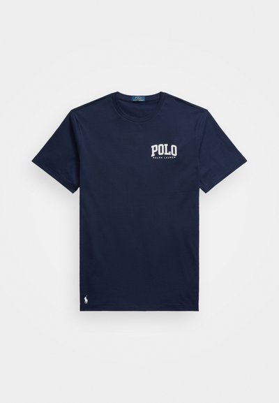 Tumši zili kokvilnas T-krekli ar īsām piedurknēm, uz kreisā krūšu kabatas ir balta izšūta "POLO" logo un neliels logo apakšmalā.