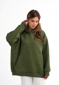 Oversized groene hoodie gemaakt van zachte stof. Voorzien van een voorzak en ribgebreide manchetten. Grote capuchon en relaxte pasvorm bieden comfort.