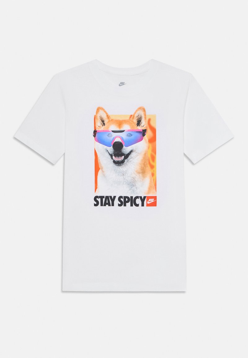 Balts Nike T-krekls ar Šiba Inu suni, kas valkā zilus saulesbrilles, un uzrakstu "STAY SPICY" ar mazu Nike logotipu uz oranša fona.
