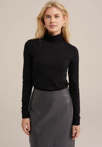 Černý dlouhý rukáv svetr s rolákem, vyrobený z hladkého materiálu, v kombinaci s přiléhavou šedou koženou sukní s elegantním designem.