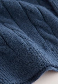 Tissu tricoté bleu marine avec un motif texturé en câble. Texture douce et duveteuse, présentant un design côtelé et des variations subtiles de teintes.