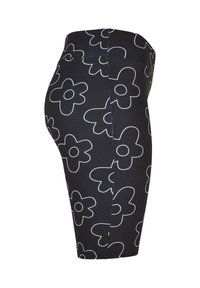 Fekete leggings fehér virágmintával. Rugalmas anyagból készült, magas derékpánttal és térdhez illeszkedő fazonnal.