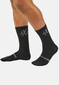 Black cotton socks with ribbed texture, featuring white logo accents on the cuff and foot. The design is below the knee.