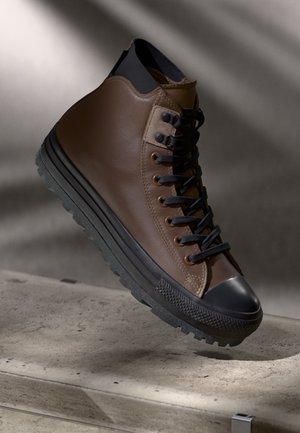 Høye sneakers i brunt lær, med svarte snorer, gummitoehette og teksturert svart såle. Glatt finish med kontrastsømmer.