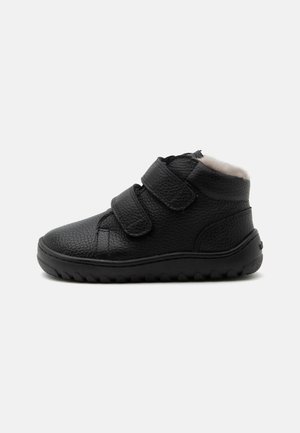Chaussure noire en cuir pour tout-petit avec deux brides Velcro, col rembourré et semelle en caoutchouc texturée, doublée en polaire blanche douce.