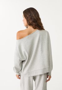 Grauer, schulterfreier Sweatshirt aus weichem Stoff. Hat eine lockere Passform, gerippte Bündchen und einen leicht abgerundeten Saum. Kombinieren Sie es mit passender Unterwäsche.