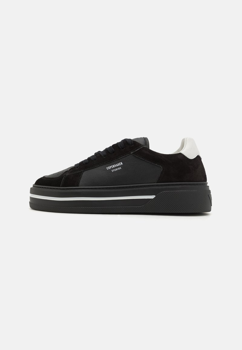 Black leather and suede sneakers with a chunky black sole. Features a white heel accent and branding text on the side. Lace-up design.