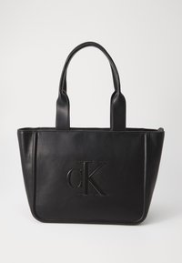 Juodas odinis rankinis krepšys su dviem rankenomis; turi įspaustą "cK" logotipą; stačiakampio formos; lygus paviršius; minimalistinis dizainas.