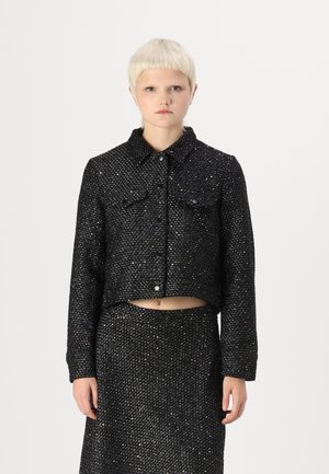 Black cropped jacket with metallic thread, collared design, two pockets, and button closure, paired with a matching black skirt.