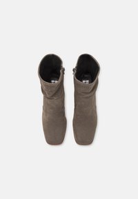 Botas de tobillo de ante gris con un diseño arrugado, punta cuadrada y cremalleras laterales. Forro interior negro, textura suave y detalles de costura mínimos.