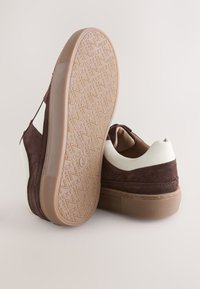Baskets en daim marron avec des touches blanches au talon, semelles en gomme plates et semelle texturée avec le motif "NEXT" et la pointure 6,5/40.