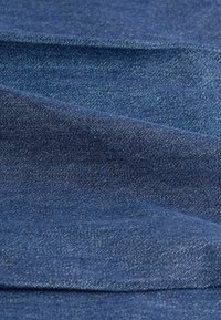 Denim fabric in dark blue with a slight sheen, featuring a smooth, woven texture and subtle, reflective threads woven throughout.