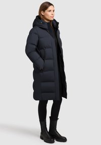 Gevoerde jas in donker marineblauw, met een capuchon, lange lengte, ritszakken en een quilted ontwerp met horizontale secties, gemaakt van gladde stof.