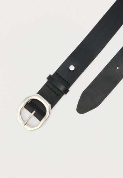 Fekete bőr öv ezüst nyolcszögletű csattal, varrott részletekkel és egy kis fémszegeccsel az öv hurka mellett, egyszínű háttér előtt.