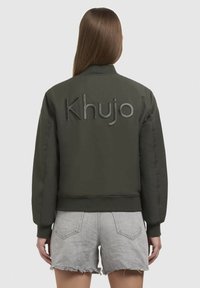 Olivovo zelená bomber bunda s rebrovaným pásom a manžetami. Na zadnej strane sa nachádza logo "Khujo" vyrazené písmenami.