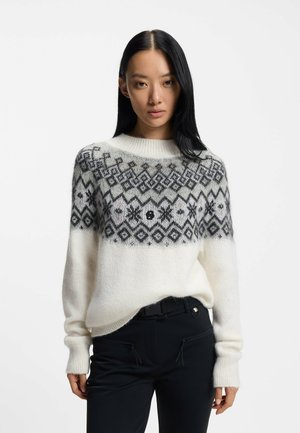 Biały sweter dziany z czarnym geometrycznym wzorem, z okrągłym dekoltem i długimi rękawami. Miękka faktura, luźny krój, z małym logo na przodzie.