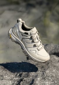 Light gray outdoor shoe, synthetic material, rounded toe, lace-up design, Vibram outsole, logo on side, and padded collar.