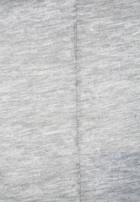 Ljust grått tyg med en något melerad textur, med en synlig söm som löper vertikalt ner i mitten.