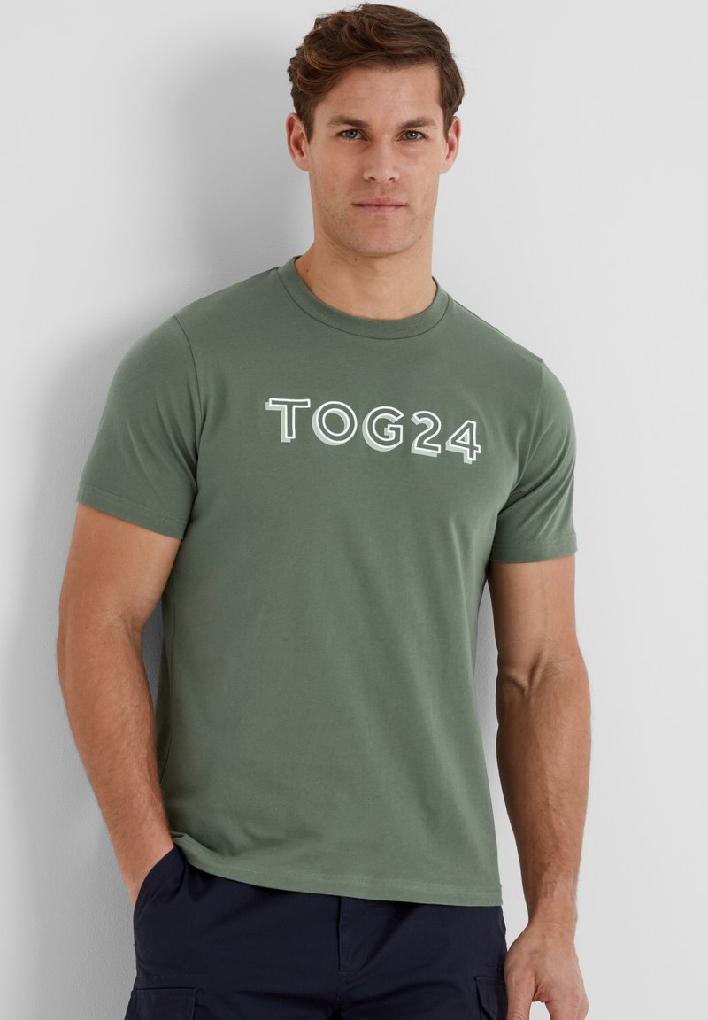 Green cotton t-shirt with a round neck and short sleeves, featuring "TOG24" printed in white on the front. Smooth, casual fit.