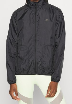 Veste coupe-vent légère et noire, avec une fermeture éclair à l'avant, un col haut et des poches zippées. Dotée d'un motif texturé subtil et de poignets élastiques.