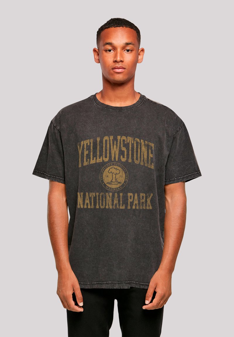 Black cotton oversized t-shirt featuring a yellow graphic text "YELLOWSTONE NATIONAL PARK" and a circular logo in the center. Crew neckline.