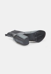 Botas de tobillo negras con tacón, con un acabado de cuero suave, un panel de tela texturizada y una suela de goma resistente; cuentan con un tacón en bloque y una lengüeta.