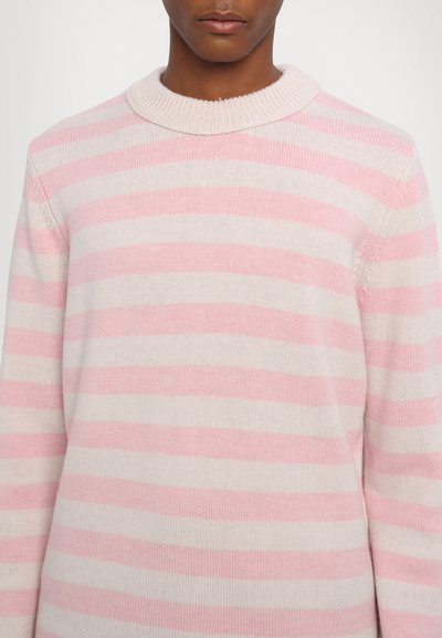 Pull rayé rose clair et crème, en maille tricotée, col rond côtelé, coupe décontractée, détails de couture visibles sur les manches.