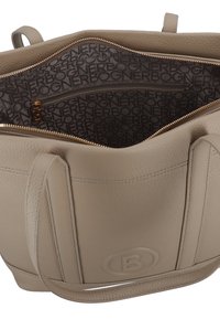 Borsa a spalla in pelle beige con texture a granuli, logo impresso sul davanti, zip dorata e foderata in tessuto marrone stampato con il testo ripetuto "BOGNER".