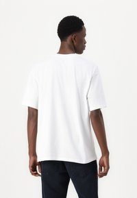 Hvid bomulds-T-shirt med korte ærmer, rund halsudskæring og en afslappet pasform. Har en glat tekstur uden synlige mønstre eller grafik.