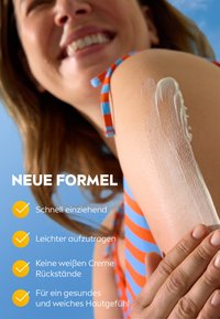 Sonnencreme auf einem nackten Unterarm mit glatter Textur, vor einem blauen Himmel. Das Model trägt einen gestreiften Badeanzug in Orange und Blau.