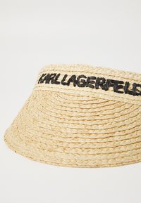 Pălărie de tip bucket din paie împletită, de culoare bej natural, cu un logo brodat negru "Karl Lagerfeld" pe bandă, având un finisaj texturat și o margine largă.