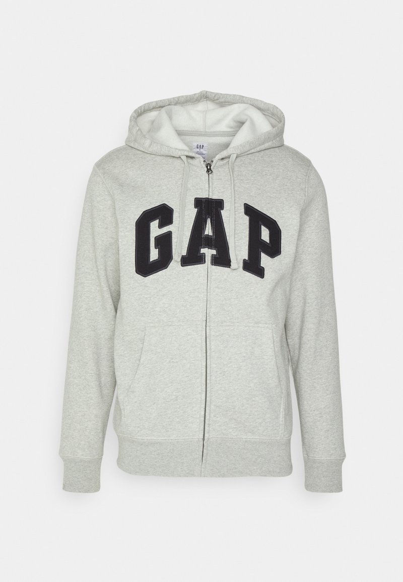 Felpa grigia con zip e tasca a marsupio frontale, con il logo "GAP" in nero. Tessuto morbido e cappuccio regolabile con cordino.