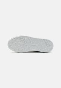 Suela de zapato de goma blanca con patrón de agarre texturizado. Presenta un diseño geométrico y un logotipo de marca claramente marcado en el costado.