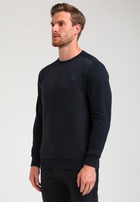 Felpa navy realizzata in tessuto testurizzato con righe diagonali, con scollatura a girocollo, maniche lunghe e un piccolo logo sul petto.