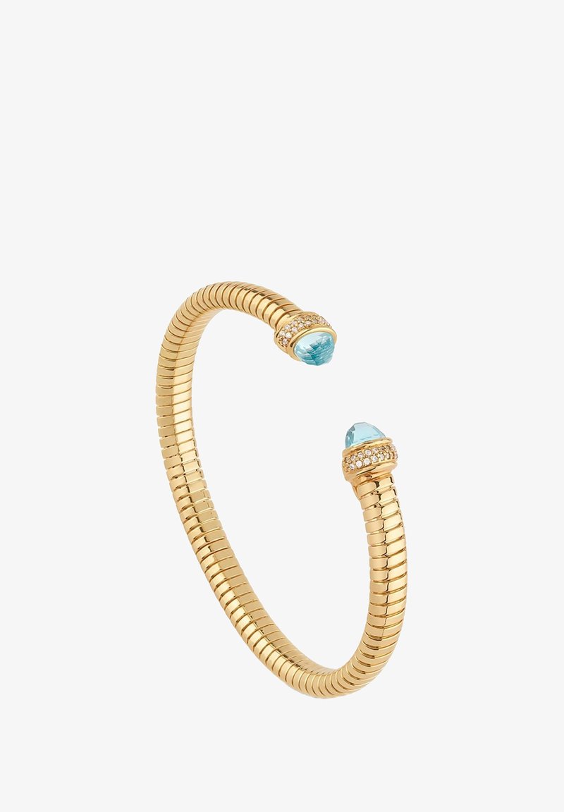 Bransoletka typu cuff w kolorze złotym, o elastycznym, spiralnym kształcie, z dwoma jasnoniebieskimi kamieniami szlachetnymi i kryształowymi akcentami na każdym końcu.