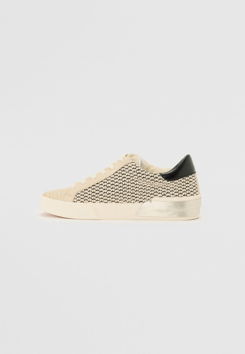 Sneaker beige e nera con motivo, punta strutturata, lacci crema e un accento nero sul tallone. Presenta un dettaglio in argento metallico sulla suola.