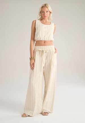 Completo beige a due pezzi composto da un top a righe corto con scollatura rotonda e pantaloni a gamba larga con vita elasticizzata e cordoncino.